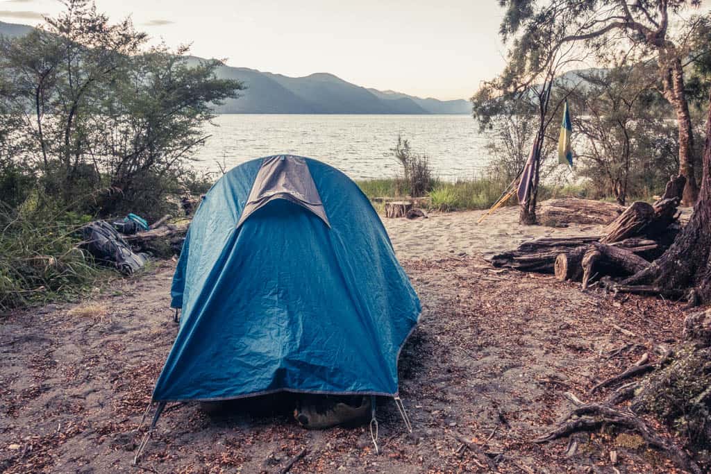 Blue MacPac tent at beach of Sabine Hut on Lake Rotoroa