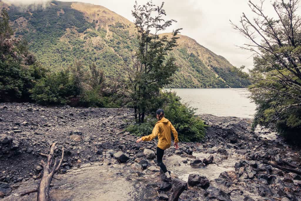 Women with yellow rain jacket crossing a stream in Saint Arnaud
