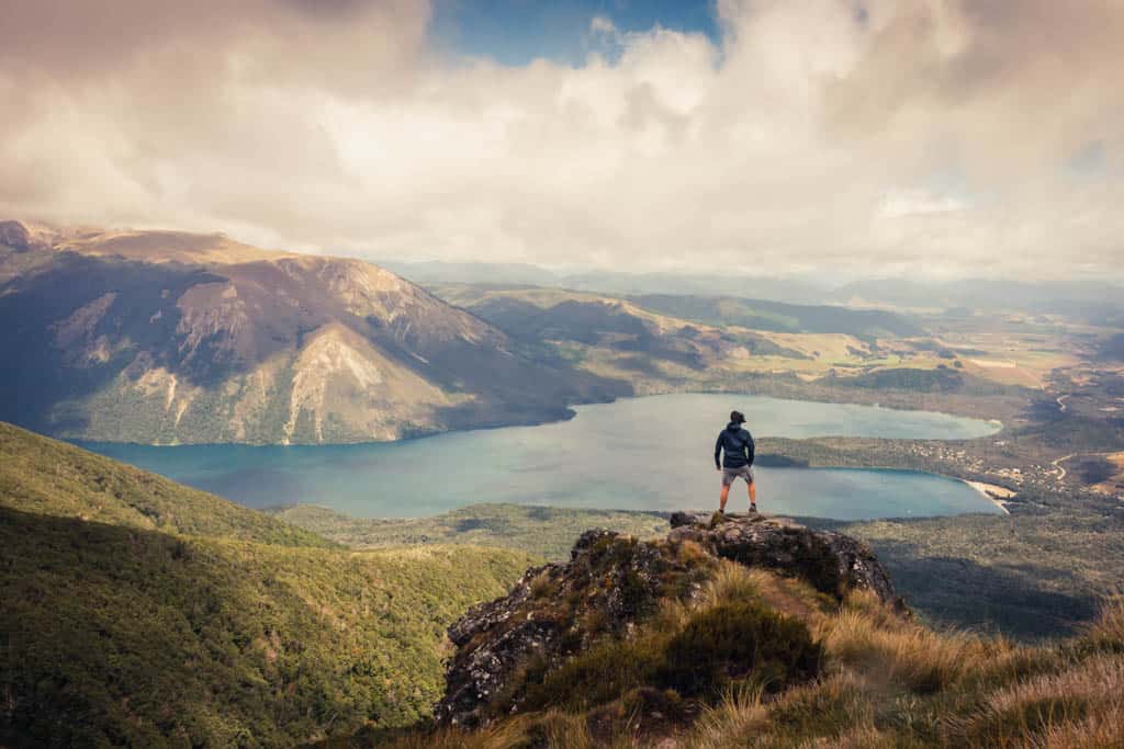 Man standing on Parachute Rocks with Lake Rotoiti in the background